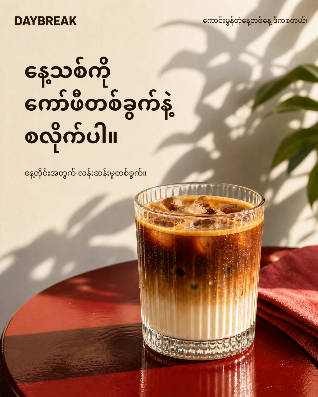 Daybreak café ad: an iced latte on a red table. Burmese copy: Start a new day with a cup of coffee. Your daily little pick-me-up.